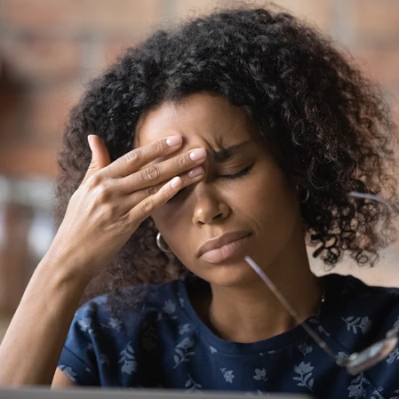 A woman holding her forehead.